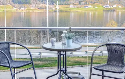 a table and chairs on a porch with a view of a lake at Stunning Apartment In Vossestrand in Vossestrand