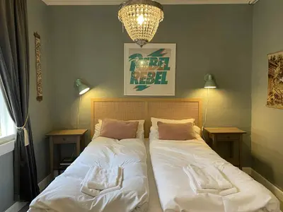 a bedroom with two beds and a chandelier at Lærdalsøren Motor Guesthouse in Lærdalsøyri