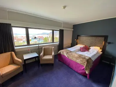 a bedroom with a bed and a chair and a window at Hotell Koselig in Kyrksæterøra