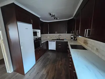 a kitchen with wooden cabinets and a white appliance at Fossen Accommodation in Geiranger