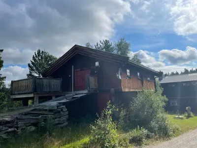 a wooden house with a balcony on a field at Måsåplassen Friisvegen Mountain Lodge in Ringebu