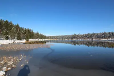 a shadow of a person standing on the shore of a lake at Måsåplassen Friisvegen Mountain Lodge in Ringebu
