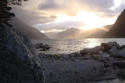 a sunset over a body of water with mountains at Fjordperlen in Eidfjord