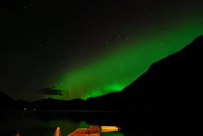 an aurora in the sky over a mountain at Fjordperlen in Eidfjord