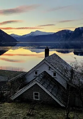 an old house sitting next to a body of water at Fjordperlen in Eidfjord