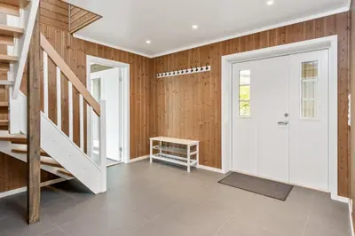 a hallway with a white door and wooden walls at Pudderhytta in Sogndal