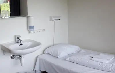 a bed and a sink in a white room at Sogndal Bed & Breakfast in Sogndal
