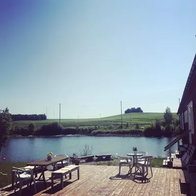 a patio with tables and chairs next to a lake at SAGA, unikt badehotell med 5 rom, sauna og badebrygge - Inderøy in Straumen