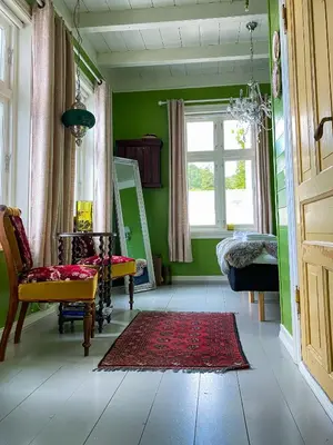 a green room with a chair and a mirror at Haaheim Gaard in Uggdal