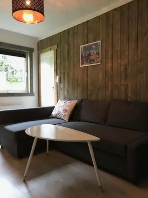 a living room with a black couch and a table at Kvamseter Lodge - Mountain Apartments in Norheimsund