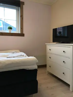 a bedroom with a bed and a dresser with a tv at Kvamseter Lodge - Mountain Apartments in Norheimsund