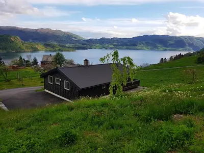 a black house on a hill next to a lake at Etne Hytter in Etnesjøen
