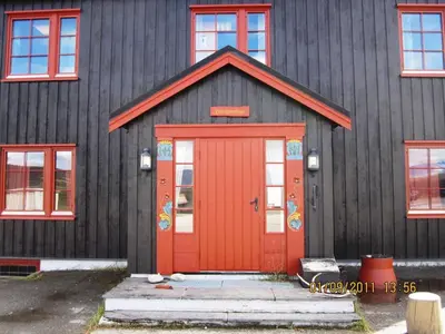 a black house with a red door and windows at Basecamp Frich`s Hjerkinn in Hjerkinn