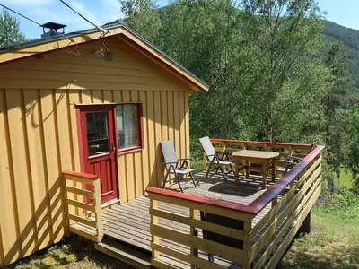 a cabin with a table and chairs on a deck at Holiday Home Turken by Interhome in Kaupanger