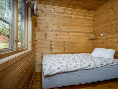 a bed in a wooden room with a window at Holiday Home Myravatnet by Interhome in Viksdalen