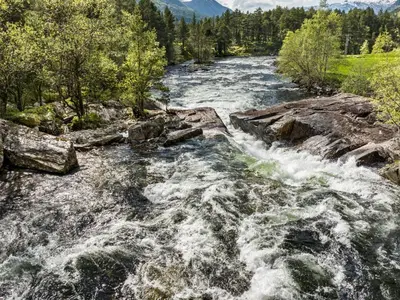 a river with rapids on top of rocks and trees at Holiday Home Myravatnet by Interhome in Viksdalen