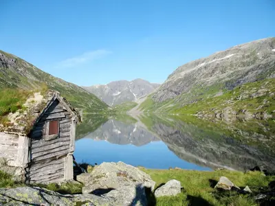 an old house sitting next to a mountain lake at Holiday Home Myravatnet by Interhome in Viksdalen