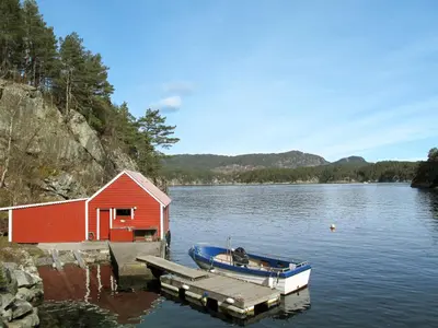 a boat docked at a dock next to a red building at Holiday Home Bjørkeneset by Interhome in Uggdal