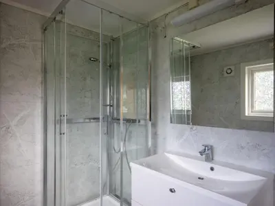 a bathroom with a glass shower and a sink at Chalet Gulehuset by Interhome in Gjelland