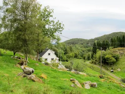 a house on a hill with green grass and rocks at Holiday Home Gamlahuset by Interhome in Bruntveit