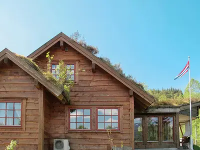 a log cabin with a flag in front of it at Chalet Elisabeth by Interhome in Eikelandsosen