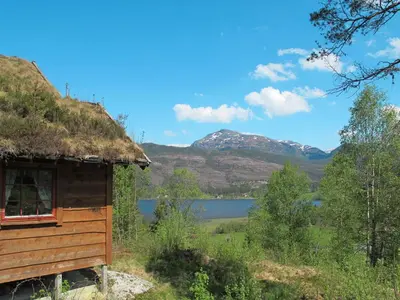 a cabin with a thatch roof and a lake at Chalet Elisabeth by Interhome in Eikelandsosen