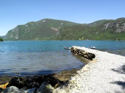 a rocky shore of a lake with mountains in the background at Holiday Home Ikjefjord by Interhome in Bjordal