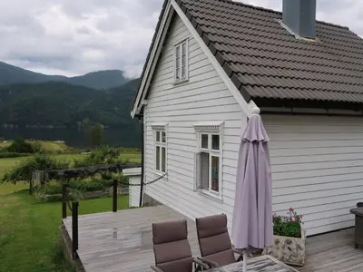 an umbrella and chairs on a deck next to a house at Holiday Home Ikjefjord by Interhome in Bjordal