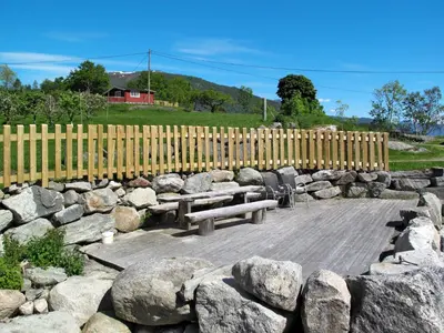 a stone wall with two benches and a fence at Holiday Home Naustvollen by Interhome in Balestrand