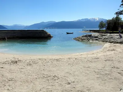 a sandy beach with a boat in the water at Holiday Home Naustvollen by Interhome in Balestrand