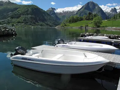 a white boat docked at a dock on a lake at Holiday Home Naustvollen by Interhome in Balestrand