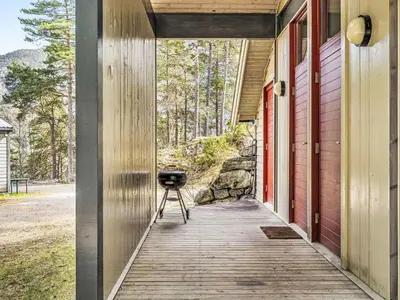 a wooden walkway to a red house with a grill on it at Holiday Home Veganeset I by Interhome in Balestrand