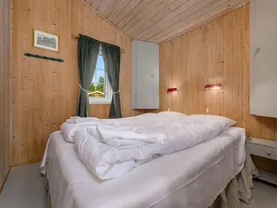 a large white bed in a wooden room with a window at Holiday Home Synnøve by Interhome in Gjølanger