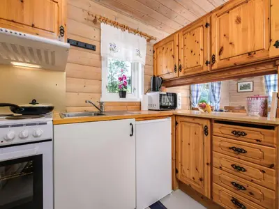 a kitchen with white appliances and wooden cabinets at Holiday Home Synnøve by Interhome in Gjølanger