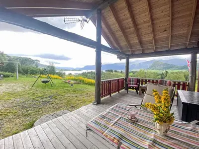 a wooden deck with a table and a swing at Holiday Home Lenebu by Interhome in Syvde