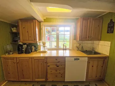 a kitchen with wooden cabinets and a sink and a window at Holiday Home Lenebu by Interhome in Syvde