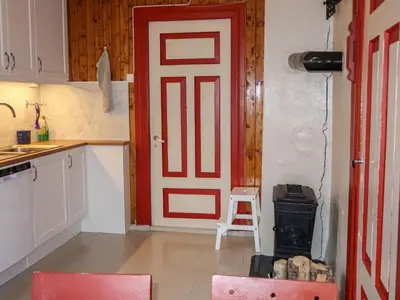 a kitchen with a red door and a stove at Holiday Home Elvehuset by Interhome in Holsen