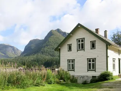 an old white house with mountains in the background at Holiday Home Elvehuset by Interhome in Holsen
