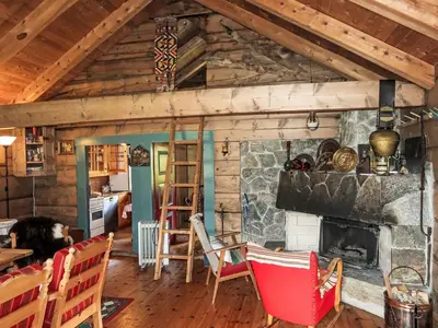 a living room with a stone fireplace and wooden ceilings at Chalet Haukedalspanorama by Interhome in Holsen