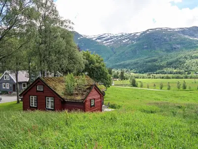 a small house in a field with mountains in the background at Chalet Haukedalspanorama by Interhome in Holsen