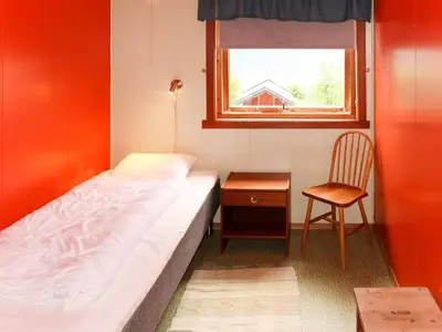 a bedroom with a bed and a chair and a window at Apartment Mjellhaugen by Interhome in Naustdal i Sunnfjord