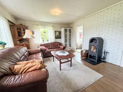 a living room with a leather couch and a wood stove at Holiday Home Kvamsvika by Interhome in Kvammen