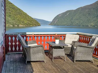 a patio with chairs and a table with a view of a lake at Holiday Home Johans Maria stova by Interhome in Arnefjord