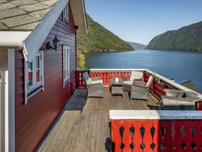 a deck of a house with chairs and a view of the water at Holiday Home Johans Maria stova by Interhome in Arnefjord