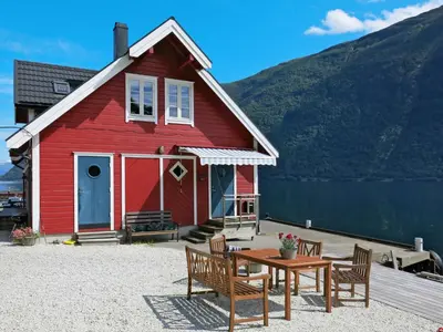 a red house with a table and chairs in front of it at Apartment Fagerdalsnipi by Interhome in Arnefjord