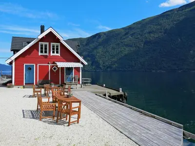 a red house on a dock next to a lake at Apartment Fagerdalsnipi by Interhome in Arnefjord