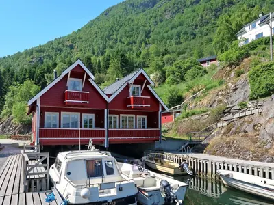 a boat is docked in front of a red house at Holiday Home Jambueggi by Interhome in Arnefjord
