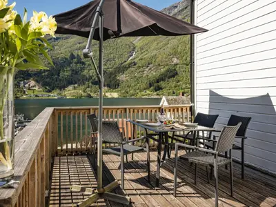 a patio with a table and chairs and an umbrella at Holiday Home Indresfjord by Interhome in Åse