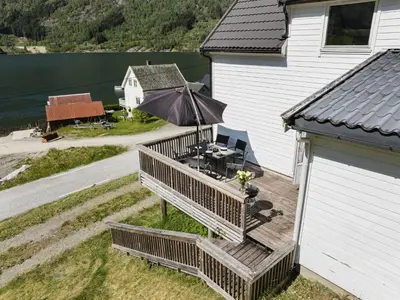 an outdoor deck with a table and an umbrella at Holiday Home Indresfjord by Interhome in Åse