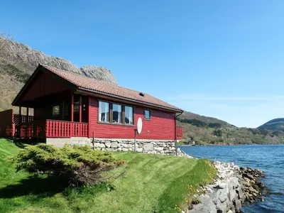 a red house on the shore of a lake at Holiday Home Nanna by Interhome in Hyllestad